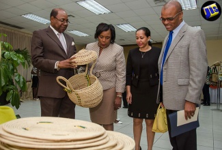 Minister of Tourism, Hon. Edmund Bartlett (left), inspects craft items at the Craft Enhancement Project Recognition and Awards Ceremony, held  on July 12, at the New Kingston Business Centre.  Others (from second left) are Craft Coordinator at the Tourism Product Development Company (TPDCo) Violet Crutchley;  Director of  the Organization of American States (OAS) Country Office, Jeanelle Van Glaanenweygel, and  Executive Director  of  TPDCo, Dennis Hickey. 