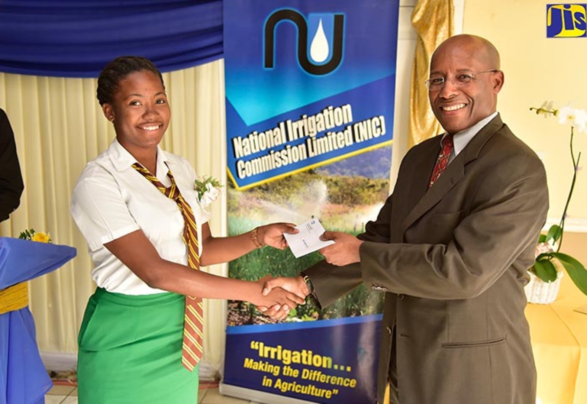 Chairman, National Irrigation Commission Limited, Senator Aubyn Hill (right), presents a  cheque to secondary-level scholarship recipient, Abigail Pollack, at the organisation’s awards ceremony, held in Kingston on Tuesday (March 27).