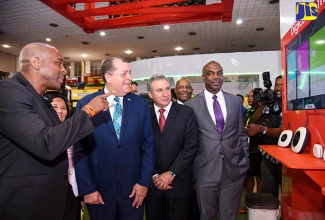 Minister of Industry, Commerce, Agriculture and Fisheries, Hon. Audley Shaw (third left), listens as General Manager, Digicel Business, Brian Bennett Easy (left), explains aspects of the ‘Digicel Eye’, following the opening ceremony for Expo Jamaica 2018 at the National Indoor Sports Centre on April 19.  Others (from right are): Vice President of Sales and Promotions, Jamaica Promotions Corporation (JAMPRO), Claude Duncan; Government Senator, Aubyn Hill; President, Jamaica Manufacturers’ Association, Metry Seaga; and President, Jamaica Exporters’ Association, Michelle Chong.  ‘Digicel Eye’ offers customers a link to the Ministry of National Security’s JamaicaEye initiative, a national closed-circuit television (CCTV) surveillance programme geared at improving public safety and security.