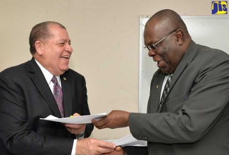 Minister of Industry, Commerce, Agriculture and Fisheries, Hon. Audley Shaw (left), exchanges Memorandum of Understanding (MOU) document with Executive Director of the Caribbean Agricultural Research and Development Institute (CARDI), Barton Clarke, at the signing held at the Ministry in New Kingston on April 25.  The MOU was signed for the refurbishing of the Bodles Research Station’s seed laboratory and storage facility in St Catherine. 