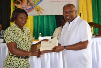 Minister without Portfolio in the Ministry of Transport, Works and Housing, Hon. Dr. Morais Guy (Right) presents resident of the Barrett Hall Housing Development, Sudar Buckall with her registered title during a presentation ceremony held at Barrett Hall in St. James on Friday (August 16). Twenty-nine new land owners received titles during the ceremony.