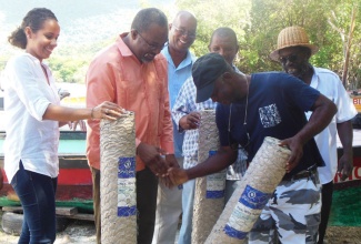 State Minister in the Ministry of Agriculture and Fisheries, Hon. Luther Buchanan (2nd left), hands over a roll of mesh wire to member of the Bluefields Bay Fishermen’s Friendly Society, Keith Wedderburn (2nd right). Occasion was the presentation of 50 rolls of wire to the fisherfolk on October 17, at the Bluefields Bay Beach in Westmoreland. Others (from left) are: National Coordinator for Caribsave Jamaica, Michelle McNaught;  Councillor for the Whitehouse Division of the Westmoreland Parish Council, Waldence Gifford; Vice Chairman of the Jamaica Fishermen’s Cooperative, Shawn Taylor; and President of the Bluefields Bay Fishermen’s Friendly Society, Livingston Thompson.