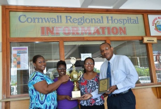 Chief Executive Officer, Cornwall Regional Hospital in St. James, Anthony Smikle (right); Medical Consultant and Head of the Accident and Emergency Department, Dr. Dena Kirnon (second right); Acting Senior Hospital Administrator, Keriesa Bell-Cummings (left); and Acting Hospital
Administrator- In-Patient Services, Camile Lewin (centre); pose with the trophy and plaque of recognition that the hospital receives for copping the top award in the Public Sector Customer Service Competition 2012/2013.
