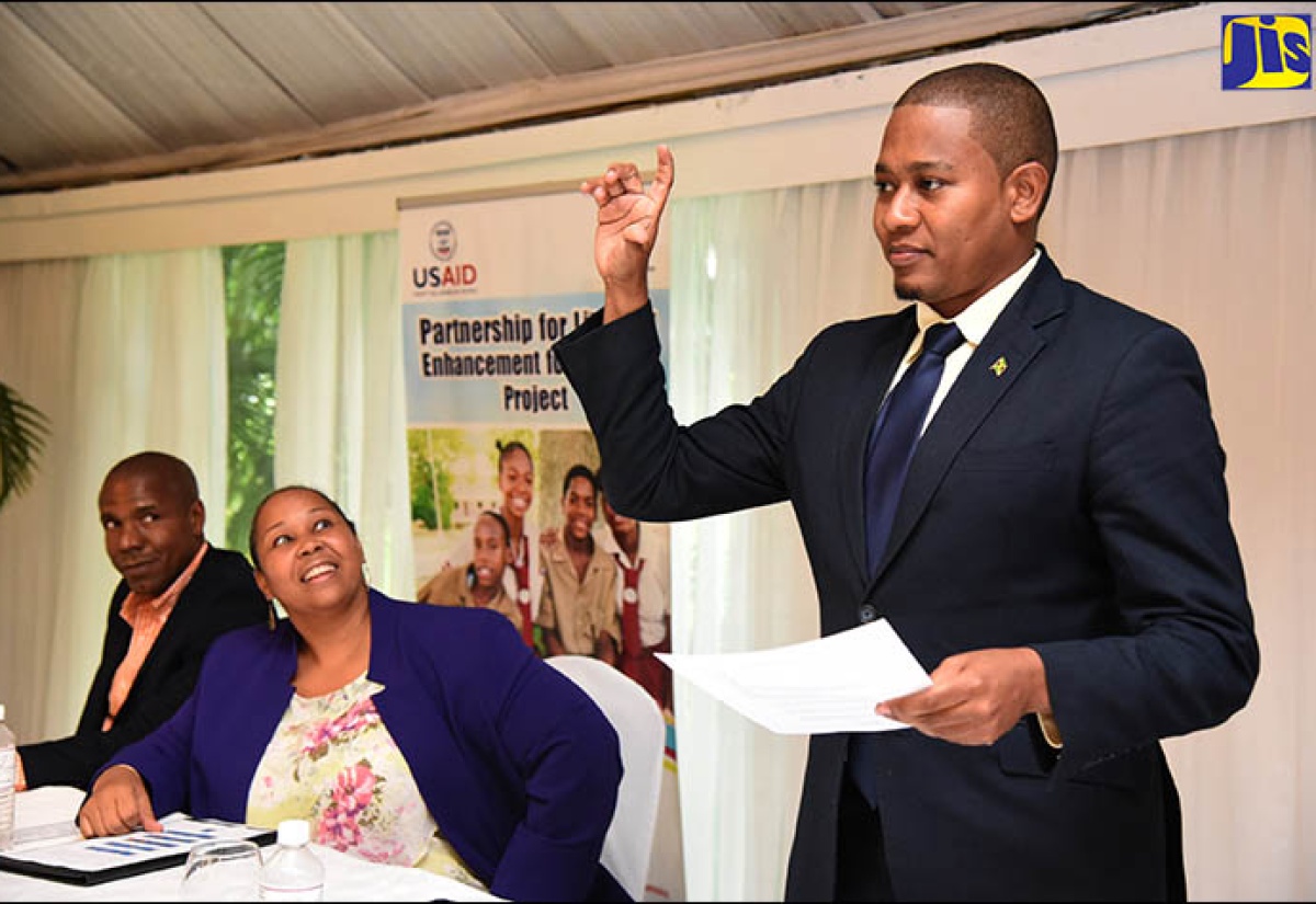 State Minister for Education, Youth and Information,  Hon. Floyd Green (right), spells his name in sign language during the launch of the Partnership for Literacy Enhancement for the Deaf Project at the Terra Nova All-Suite Hotel in Kingston recently. The project aims to increase the literacy level of hearing-impaired children. It is being implemented by the Jamaica Association for the Deaf (JAD), in partnership with international funding agency, the United States Agency for International Development (USAID).  Observing are Acting Mission Director for USAID, Rebecca Robinson (centre) and Chairman of the Executive Board of the Jamaica Association for the Deaf, Christopher Williams.