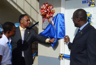 Education, Youth and Information Minister, Senator the Hon. Ruel Reid (right) and Managing Director of the Jamaica Social Investment Fund (JSIF), Omar Sweeney (left), unveil a plaque to officially hand over a new classroom block at the Mandeville Primary and Junior High School on November 2. At left is Head Boy of the school, Kevanny Gayle.