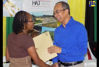 Minister without Portfolio in the Ministry of Economic Growth and Job Creation, Hon. Dr. Horace Chang (right), presents Norwood resident, Curdillio Evans, with her land title. Ms. Evans, who has been living in the community for over 20 years, was among more than 100 residents to receive their titles during a ceremony held recently at the Norwood Seventh-day Adventist Church in St. James.