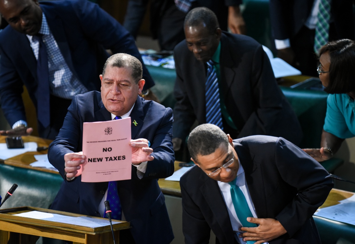 Minister of Finance and the Public Service, Hon. Audley Shaw (left), holds up a paper declaring NO NEW TAXES for the 2018/19 fiscal year, while Prime Minister, the Most Hon. Andrew Holness (right), and other Members of Parliament show their support. Minister Shaw was opening the 2018/19 Budget debate in the House of Representatives on March 8.  