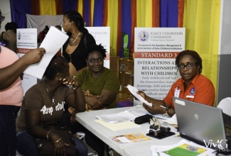 Early Childhood Commission (ECC) Inspector, Marlene Turner (right), attends to participants registering for the ECC’s Region Two Certification Fair in Buff Bay, Portland, in October 2016.