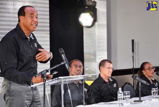 Economic Growth Council (EGC) Chairman, Michael Lee-Chin (at podium), addresses its quarterly briefing on January 26 at The Jamaica Pegasus hotel in New Kingston.  Seated (from left) are: EGC Deputy Chairman, Ambassador Nigel Clarke; and  members, Adam Stewart and Pat Ramsay.