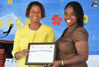 Early Childhood Commission (ECC) Acting Executive Director, Karlene Deslandes (left), presents the ECC certification to Principal of Jamaica House Basic School, Veronica Parkinson-Burnett, during a ceremony at the institution in St. Andrew on Tuesday (March 7). The certification signals the institution’s attainment of the ECC’s 12 operational standards.