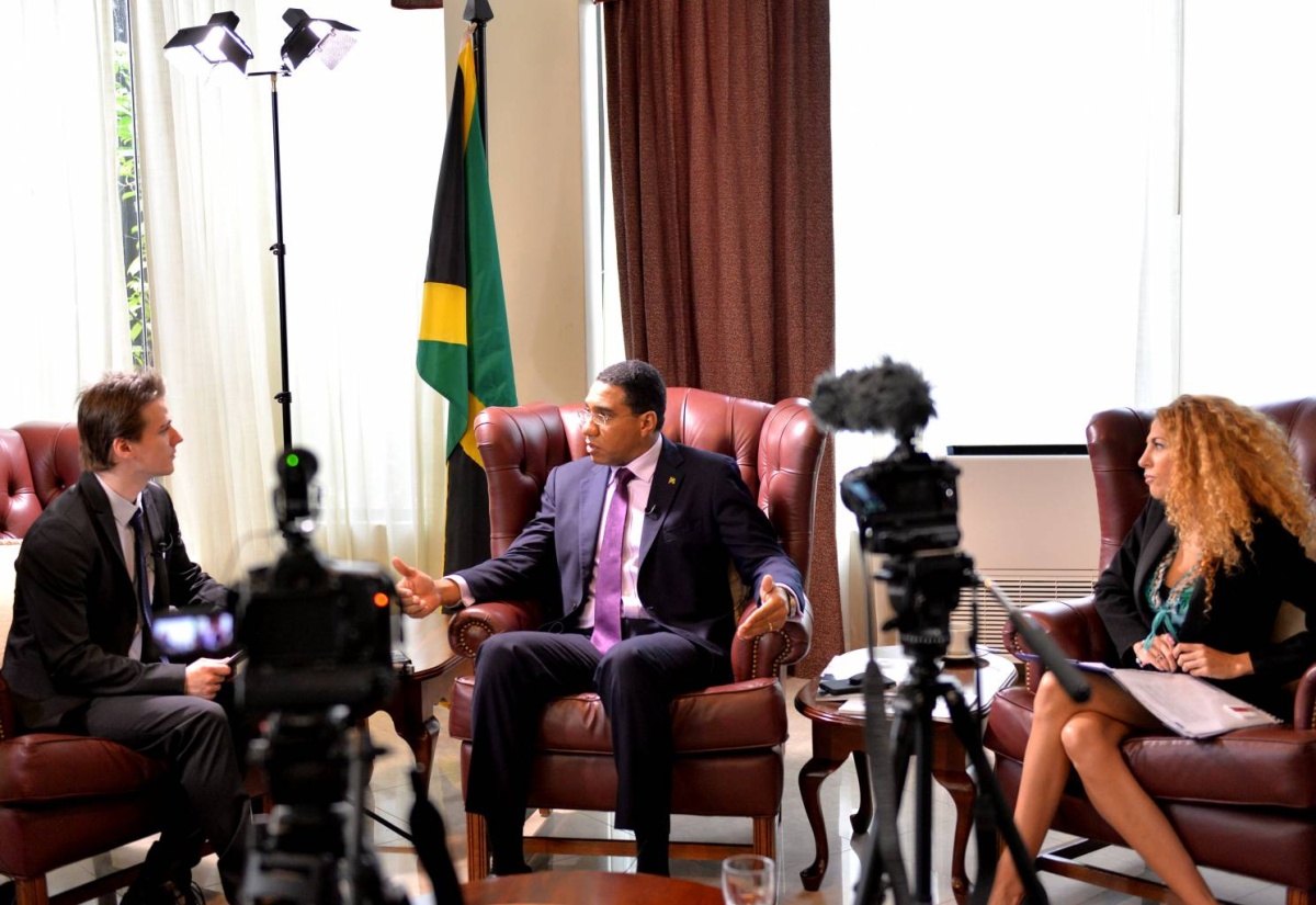 Prime Minister, the Most Hon. Andrew Holness (centre), responds to a question posed by Editor-in-Chief for World INvestment NEws (WINNE), Stan Aron (left), during an interview conducted at the Office of the Prime Minister (OPM) on Wednesday, April 13. Also pictured is Regional Market and Client Director for WINNE, Stéphanie Huertas.