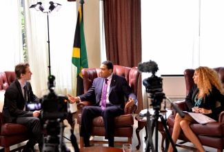 Prime Minister, the Most Hon. Andrew Holness (centre), responds to a question posed by Editor-in-Chief for World INvestment NEws (WINNE), Stan Aron (left), during an interview conducted at the Office of the Prime Minister (OPM) on Wednesday, April 13. Also pictured is Regional Market and Client Director for WINNE, Stéphanie Huertas.