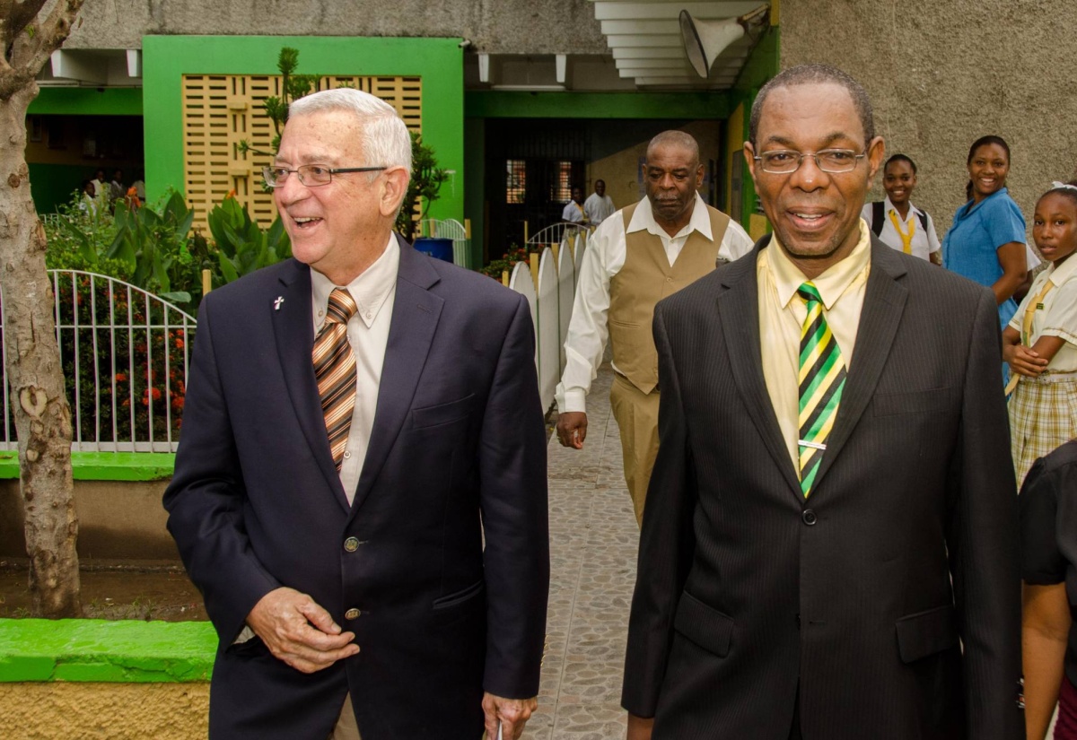 Education Minister, Hon. Rev. Ronald Thwaites (left), is escorted to the Edith Dalton James High School auditorium by Principal, Ray Howell, for Thursday’s (October 30) dedication and formal opening ceremony for five new classrooms and a library resource centre, at the institution’s Duhaney Park campus in St. Andrew. Rev. Thwaites was the guest speaker.