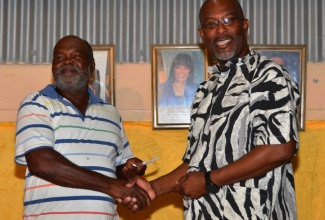 State Minister in the Ministry of Agriculture and Fisheries, Hon. Luther Buchanan (right),  presents a voucher to  Egbert Lawrence, one of over 70 farmers from Westmoreland, who have received support under the Ministry’s Agricultural Production Incentive Programme (APIP), which was launched at the New Works Primary School in the parish on January 21.