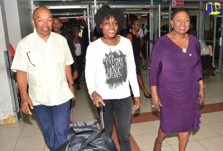 Minister of Culture, Gender, Entertainment and Sport, Hon. Olivia Grange (right) and President of the Jamaica Athletics Administrative Association (JAAA), Dr. Warren Blake (left), welcome Olympic sprint champion Elaine Thompson, on her arrival at the Norman Manley International Airport in Kingston on September 13. The Ministry hosted a welcome ceremony at the airport for six  Maximising Velocity and Power (MVP) track club  athletes; Coach, Stephen Francis, and other team members, who were returning to the island after competing in the Olympic Games in Rio de Janeiro, Brazil and the IAAF Diamond League series in Europe.