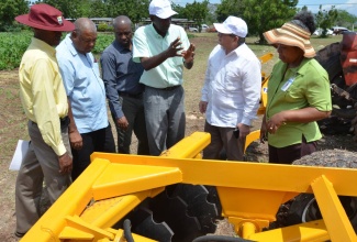 Minister without Portfolio in the Ministry of Industry, Commerce, Agriculture and Fisheries, Hon. J.C. Hutchinson (fourth left), makes a point to Cuban Ambassador to Jamaica, His Excellency Bernardo Guanche Hernandez (fifth left), at a demonstration of agricultural implements, manufactured in Cuba, at the Bodles Research Station, in Old Harbour, St. Catherine, on April 19. Others (from left) are: Director General in the Ministry, Don McGlashan; Chief Executive Officer at the Rural Agricultural Development Authority (RADA), Lenworth Fulton; Chief Technical Director in the Ministry, Dermon Spence; and  Principal Research Director at the Ministry, Dr. Lisa Myers-Morgan.