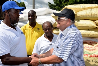 Minister of Industry, Commerce, Agriculture and Fisheries, Hon Karl Samuda (right), greets dairy farmer Oral Wallace (left), during a ceremony for the handing over of $5 million worth of fertilizer to dairy farmers from Clarendon, St. Elizabeth and St. Thomas at the Rhymesbury Cooperative Building in Clarendon on Friday (February 16). Looking on are Chairman of the Jamaica Dairy Development Board (JDDB), Donald Elvey (2nd left); and  Chairman of the Rhymesfield Dairy Farmers Cooperative, Derrick Walker.