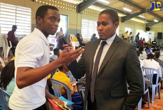 State Minister in the Ministry of Education, Youth and Information, Hon. Floyd Green (right), listens to a question from one of the students who attended the CAP and CAPE symposium, held at St. Elizabeth Technical High School in Santa Cruz, St. Elizabeth, on April 26.