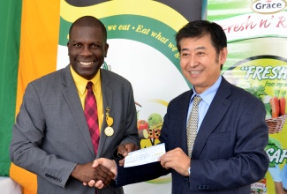 Political Counsellor  at the Chinese Embassy, Mr. Xia Ogushun  (right), presents a cheque for the purchase of 200 water tanks  for farmers, to  President of the Jamaica Agricultural Society (JAS), Senator Norman Grant, at the  ‘Eat Jamaican’ Day exposition, held today (November 25) on the grounds of the Jamaica 4-H Clubs, in Kingston.  