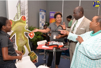 Education, Youth and Information Minister, Senator the Hon. Ruel Reid (2nd right), and Managing Director of Make Your Mark Consultants, Jacqueline Coke-Lloyd (right), are shown displays mounted at the booth of technology firm, Iprint Digital, by Sales Manager, Sophia Somers Williams (2nd left). Looking on is the entity’s Sales Administrator, Monique Blake. The occasion was the opening day of the eighth annual two-day Make Your Mark Consultants Middle Managers’ Conference, at The Jamaica Pegasus hotel in New Kingston on Tuesday, April 25.