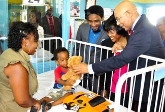 Their Excellencies and Dr. Andrei Cooke interacting with a patient while her parent looks on.