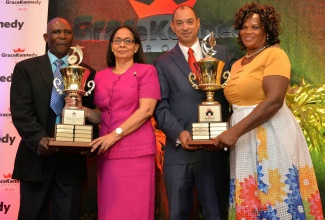 Minister of Labour and Social Security, Hon. Shahine Robinson (second left) and Group Chief Executive Officer for GraceKennedy Limited, Senator Don Wehby (third left), present trophies to winners of the GraceKennedy/Heather Little-White Household Worker of the Year Awards, Anthony Houston (left) and Cherilene Williams-Case (right) during the awards ceremony, held on October 5 at The Jamaica Pegasus hotel in Kingston.  