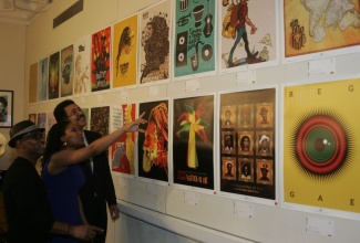 Ambassador to the United States, His Excellency Stephen Vasciannie (right), listens attentively as member of the International Reggae Poster Contest (IRPC), Kathryn Buford (centre), explains the significance of one of the posters on display at the Embassy of Jamaica.  Looking on (at left) is founder of the IRPC, Michael Thompson.  The exhibition, which was officially opened by Ambassador Vasciannie at the Embassy on  November 14,  will run for one week.  