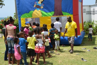 President of the Harris Family Vision Foundation, Michael Harris (right), looks on as children wait to take their turn in the bounce house, during a back-to-school treat and health fair hosted by the foundation recently, at the Fletcher's Grove Baptist Church in Sandy Bay, Hanover.