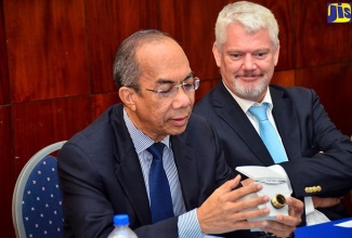 Minister without Portfolio in the Ministry of Economic Growth and Job Creation, Hon. Dr. Horace Chang (left), examines one of the 450,000 new high tech electronic water meters to be supplied by German company, Diehl Metering to the National Water Commission (NWC). Looking on is Ambassador of the Federal Republic of Germany, His Excellency Joachim Christoph Schmillen. Diehl was awarded a US$43.9 million contract to supply the meters for installation islandwide. Dr. Chang, along with principals of the NWC and Diehl Metering, signed the contract on Friday (Dec. 15) during a ceremony at Jamaica House.