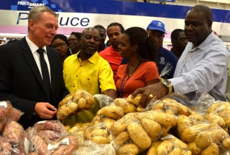 Counsellor and Head of  Development Cooperation at the Canadian High Commission, Walter Bernyck (left); and Chief Technical Director in the Ministry of Industry, Commerce, Agriculture and Fisheries, Dermon Spence (2nd left), examine local potatoes on the shelves at Pricesmart, while representative of the wholesale retailer, Donna-Marie Ford (2nd right), looks on. The occasion was a tour of the Red Hills Road facility by a 26-member regional delegation, which participated in a one week study tour of Jamaica to learn best practices in Irish potato production. The visit was sponsored by the Canadian Government through the Promotion of Regional Opportunities for fresh Produce through Enterprises and Linkages (PROPEL) project.