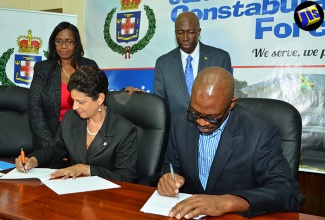 Commissioner of Police, Dr. Carl Williams (seated right) and Pro-Vice Chancellor and Principal, University of the West Indies (UWI), Open Campus, Dr. Luz Longsworth (seated left) sign  Memorandum of Understanding (MOU)  at the Office of the Police Commissioner in St. Andrew, on August 8. Through the MOU, members of the Jamaica Constabulary Force (JCF) will benefit from the academic programmes and other educational initiatives through the Open Campus. Others (from left) are Programme Coordinator, UWI Open Campus, Dr. Beverly Shirley and Assistant Commissioner, Norman Heywood. 