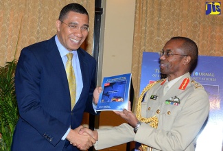 Prime Minister, the Most Hon. Andrew Holness (left), accepts a copy of the Caribbean Journal of Strategic and Security Studies from Chief of Defence Staff, Jamaica Defence Force (JDF), Major General Rocky Meade, at the launch of the journal at the Mona Visitors’ Lodge, University of the West Indies (UWI) on January 21.