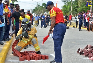 A Firefighter (left) under the watchful eye of an adjudicator (right), attaches a nozzle to a hose, as he participates in the ‘Fireman’s Challenge’ at the Open Day and Expo, hosted by the Jamaica Fire Brigade at the Waterfront, Downtown Kingston on November 2.