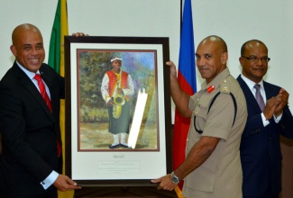 Chief of Defence Staff, Major  General Antony Anderson (right), makes a presentation to President of the Republic of Haiti, His Excellency Michel Martelly, as Minister of National Security, Hon Peter Bunting (right),  applauds, during the President’s State Visit last week.  