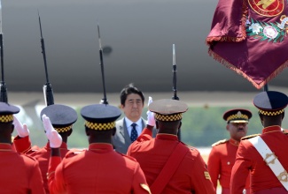 Prime Minister of Japan, His Excellency Mr. Shinzo Abe (centre), being saluted by members of the Jamaica Defence Force (JDF), on his arrival at the Norman Manley International Airport, today (September 30), for a two-day official visit.