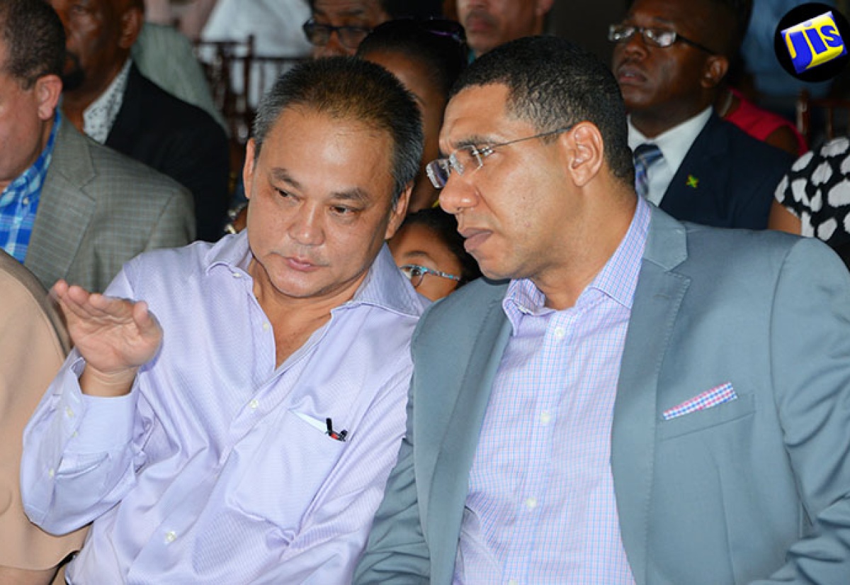 Prime Minister, the Most Hon.  Andrew Holness (right), listens keenly to Chairman and Chief Executive Officer (CEO) of Juici Patties, Jukie Chin, at the official opening of ‘Empowerment Park’ by the company at Clarendon Park, on July 10. 