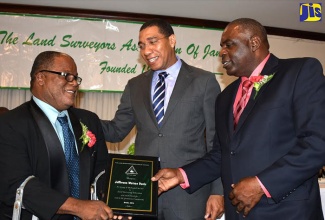 Prime Minister, the Most Hon. Andrew Holness (centre), congratulates Jefferson Davis (left), who was awarded for long and dedicated service to land surveying education at the Land Surveyors Association of Jamaica’s (LSAJ) annual dinner and awards function at The Jamaica Pegasus hotel in New Kingston on October 28.  President of the LSAJ, Valentine McCook, made the presentation.