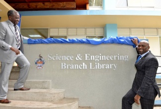 Minister of Science, Energy and Technology, Dr. the Hon. Andrew Wheatley (right), and  Deputy Principal of the University of the West Indies (UWI), Mona Campus, in St. Andrew, Professor Ishenkumba Kahwa (left), unveil a sign at the rebranded UWI Science and Engineering Branch Library, today (May 17).