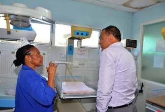 Minister of Health, Hon. Dr. Christopher Tufton (right), listens intently to Director of Nursing Services at the Spanish Town Hospital, Sherleen Marshal Davis, as she explains how babies are cared for in the nursery. Occasion was a tour of the hospital in St. Catherine on June 9.