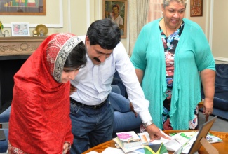 Malala Yousafzai, the Pakistani schoolgirl who was shot by the Taliban last year, and her father Ziauddin Yousafzai,  view  a variety of books and poems, letters and essays  done for Malala by girls of Hampton High School in St. Elizabeth, Jamaica. Malala and her father,  on Friday (July 19), visited the High Commission in London, where High Commissioner, Her Excellency, Aloun Ndombet-Assamba (right), made the presentation.