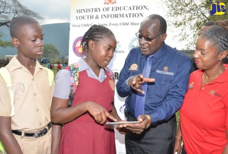 Education, Youth and Information Minister, Senator the Hon. Ruel Reid (2nd right), engages grade-10 student of the Spanish Town High School in St. Catherine, Chamoya Williams (2nd left), in a mathematics exercise on a tablet. Occasion was the National Mathematics Expo at the Mona Campus of the University of the West Indies on March 9. Looking on are (from left) National Mathematics Coordinator, Dr. Tamika Benjamin; and grade-eight student of the Calabar Infant Primary and Junior High School, Roshane Hylton.