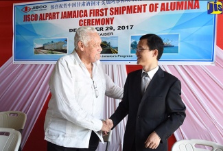 Transport and Mining Minister, Hon Mike Henry (left), greets Chargé D'Affaires at the Embassy of the People's Republic of China in Jamaica, Yang Wenxu, during a ceremony to mark the first shipment of alumina from JISCO Alpart in St. Elizabeth to China, at Port Kaiser in December 2017.        