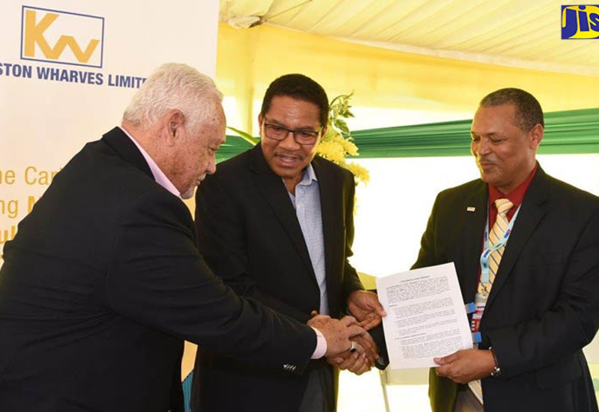 Minister of Transport and Mining, Hon. Mike Henry (left), congratulates Chief Executive Officer of Kingston Wharves Limited (KWL), Grantley Stephenson (centre), after signing and handing over the lease arrangements for the KWL’s Global Auto Logistics Centre. Sharing the moment is President and Chief Executive Officer of the Airports Authority, Audley Deidrick. Occasion was the launch of the facility located at Tinson Pen in St. Andrew on Friday (December 15).