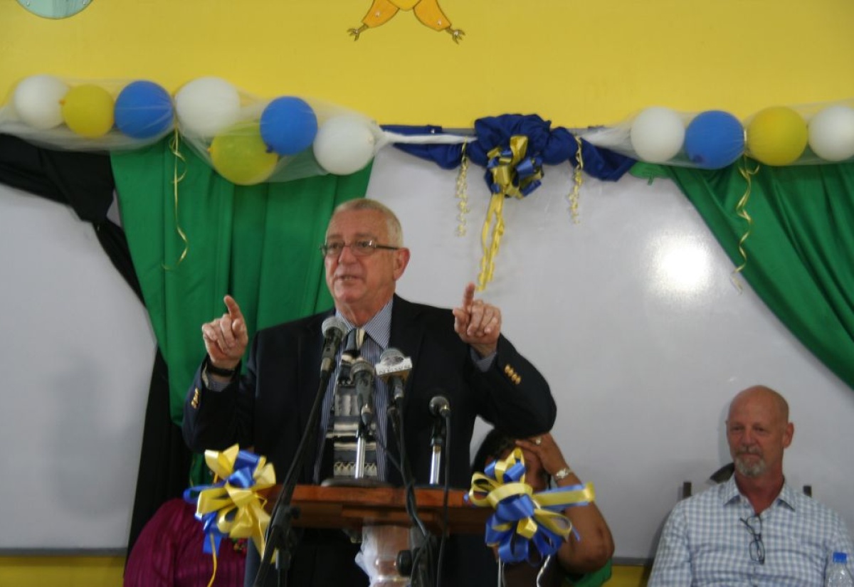 Minister of Education, Hon. Rev. Ronald Thwaites (left), address a ceremony to mark the official re-dedication of the Moreland Hill Primary School in Westmoreland, held on Thursday (Nov. 7) on the school grounds. Looking on in background are Principal of the school, Alecia Laing (partly hidden) and President of the Rockhouse Foundation, Peter Rose. 
