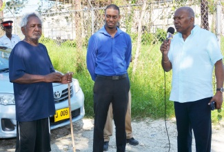 Minister Without Portfolio, Ministry of Transport, Works, and Housing, Hon. Dr Morais Guy (right), addressing residents of Paradise, one of 12 informal settlements in Central Westmoreland which he visited last week. Also pictured is Central Westmoreland Member of Parliament, Dwayne Vaz (centre), who accompanied Dr. Guy, and a resident of the community.