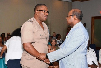 Minister of Tourism, Hon. Edmund Bartlett (right), is  greeted by Deputy Superintendent,  Adrian Hamilton, of the Negril Police at a  meeting with tourism stakeholders at Swept Away Resort Hotel in Negril on June 24. 