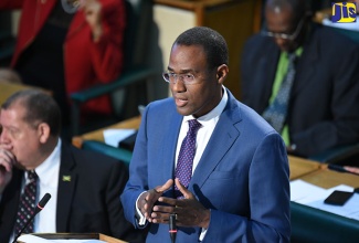 Minister of Finance and the Public Service, Dr. the Hon.  Nigel Clarke, addresses the House of Representatives on April 11. At left is Industry, Commerce, Agriculture and Fisheries Minister, Hon. Audley Shaw. 