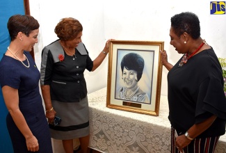 Culture, Gender, Entertainment and Sport Minister, Hon. Olivia Grange (right); and Minister of Foreign Affairs and Foreign Trade, Hon. Kamina Johnson Smith (left), admire a portrait of late female political pioneer, Rose Agatha Leon, being shown to them by her daughter, Gloria Millwood. Occasion was the annual Rose Leon Memorial Lecture held recently at the Petroleum Corporation of Jamaica (PCJ) Auditorium, St. Andrew.