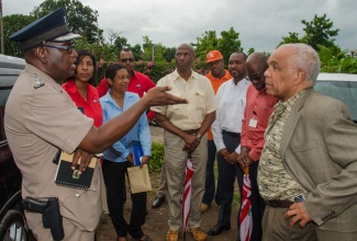 Minister of Transport, Works and Housing, Dr. the Hon. Omar Davies (right, foreground), listens to a point from Senior Superintendent of Police (SSP), Steve McGregor (left, foreground). The Minister, who is also Member of Parliament for South St. Andrew, was visiting fire victims in Hopeful Village, Arnett Gardens on March 13. The fire, which occurred on March 6, claimed the lives of three children. The Government and private sector stakeholders are collaborating to determine the extent of assistance to be provided to the fire victims