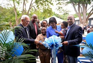 Prime Minister, the Most Hon. Portia Simpson Miller (3rd right), is assisted by Head Boy at the McIntosh Memorial Primary School in Royal Fats, Manchester, John Wayne Sinclair (3rd left), to cut the ribbon marking Friday’s (November 27) official opening of a new eight-classroom block at the school, built at a cost of over $25 million. Others (from left) are: Education Minister, Hon. Rev. Ronald Thwaites; Permanent Secretary, Ministry of Education, Dr. Maurice Smith; Permanent Secretary, Office of the Prime Minister (OPM), Elaine Foster-Allen; and National Security Minister and Member of Parliament for Central Manchester, where the school is situated, Hon. Peter Bunting.